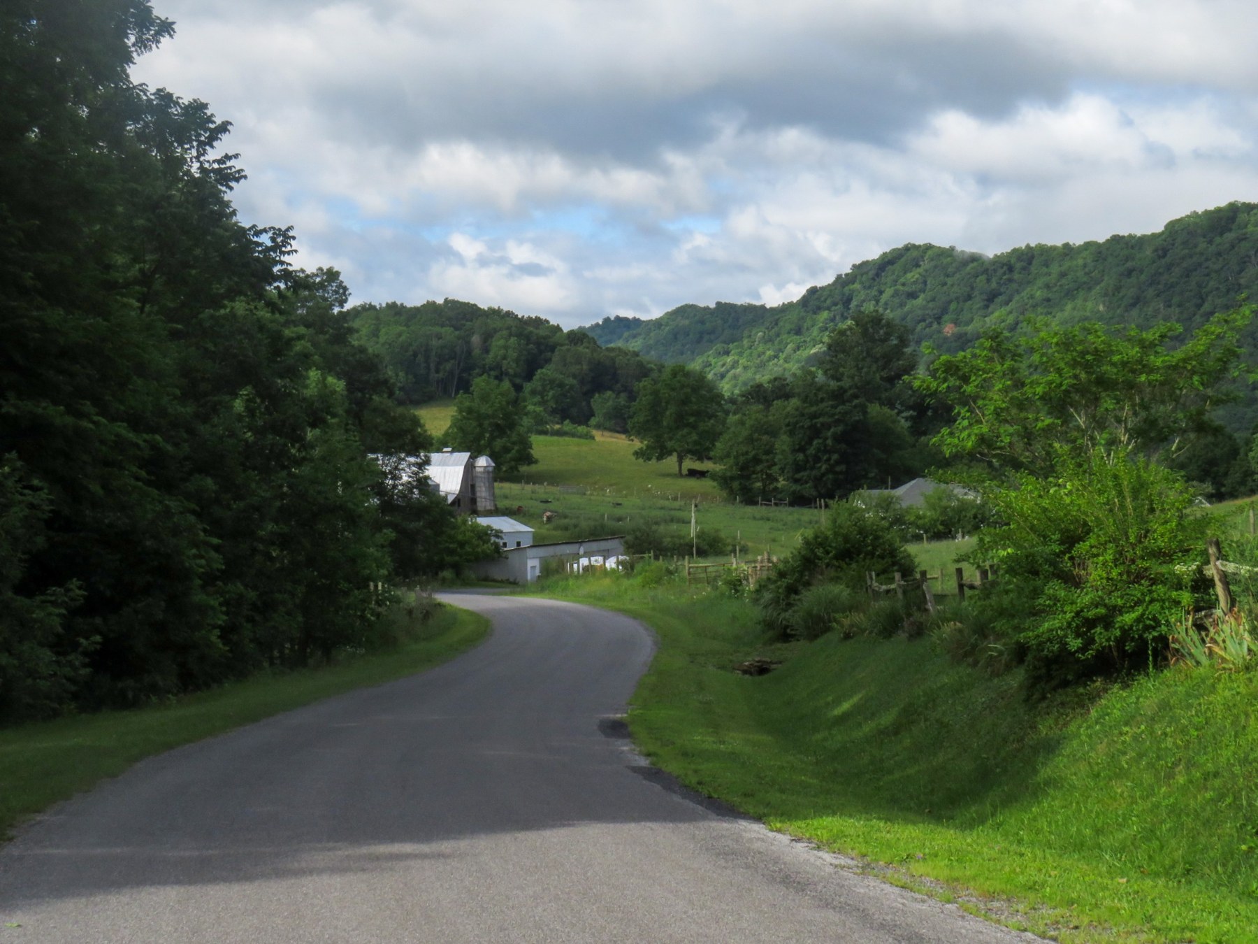 A country road curving toward farm buildings