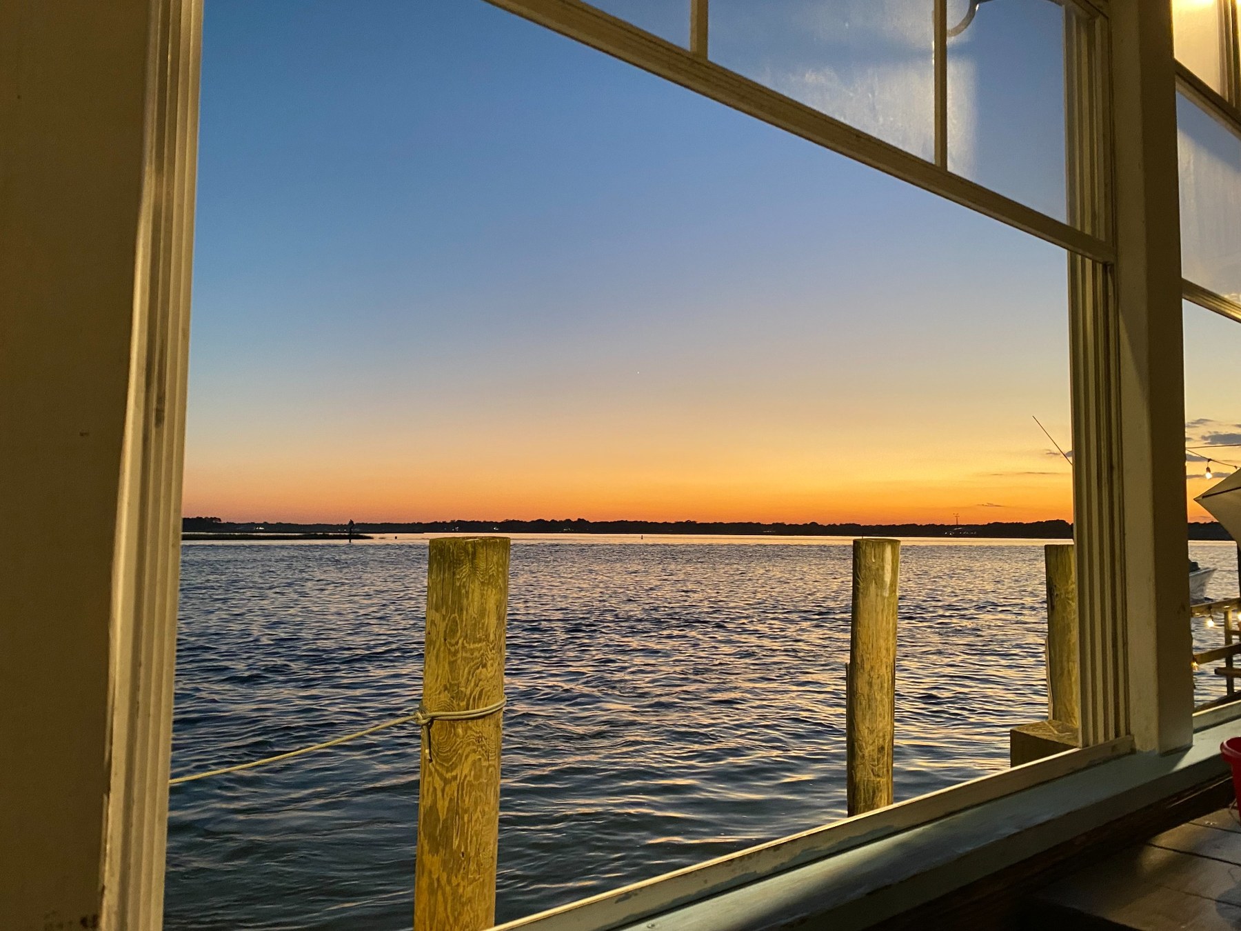 Sunset over water viewed through a window
